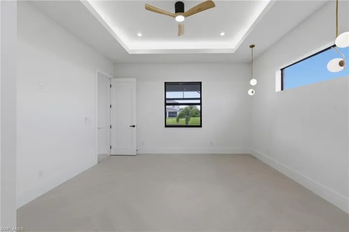 Spare room with a ceiling fan, a raised ceiling, and recessed lighting