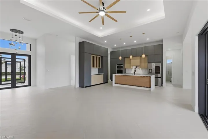 Kitchen featuring open floor plan, a tray ceiling, modern cabinets, light countertops, and stainless steel appliances