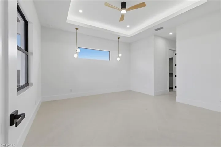 Empty room featuring a ceiling fan, a raised ceiling, and recessed lighting