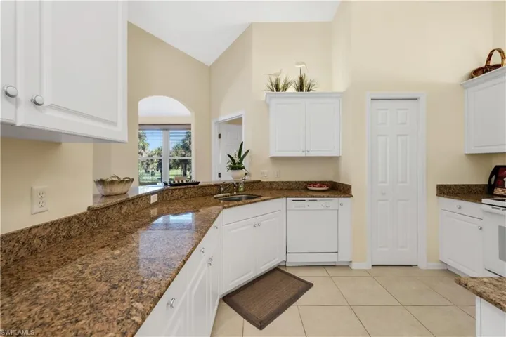 Kitchen featuring White Cabinets, High Vaulted Ceiling, White Appliances, Granite Counters