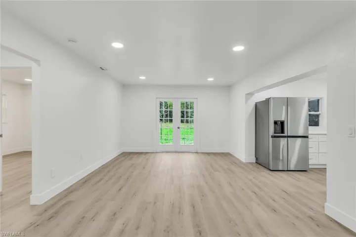 Unfurnished living room with recessed lighting, french doors, and light wood-style flooring