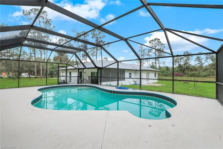 Outdoor pool featuring a yard, a sunroom, a patio area, and a lanai