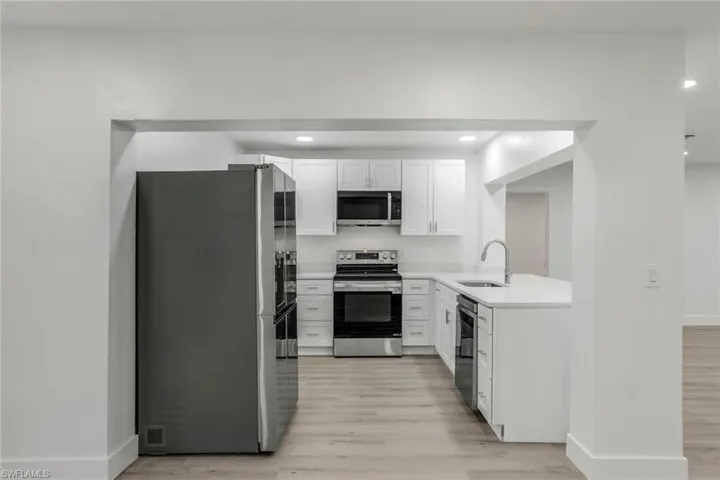 Kitchen with appliances with stainless steel finishes, white cabinetry, light wood-style flooring, and recessed lighting