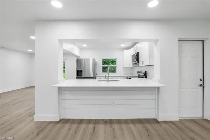 Kitchen featuring white cabinetry, stainless steel appliances, light wood-type flooring, recessed lighting, and a peninsula