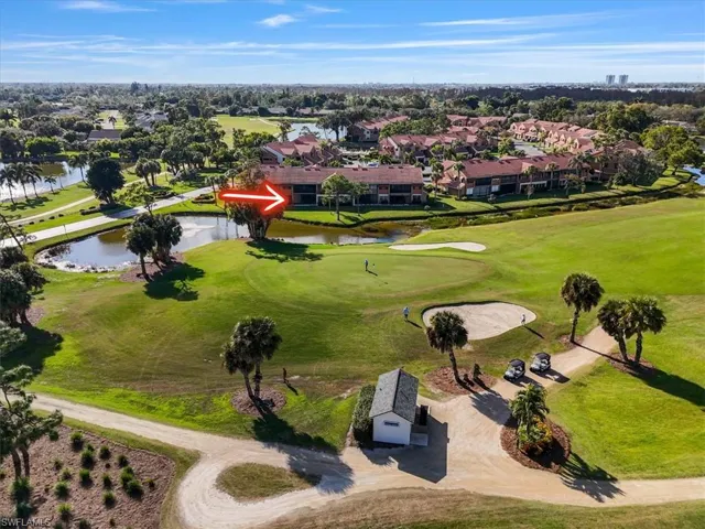 Aerial view of residential area featuring a golf course and a nearby body of water