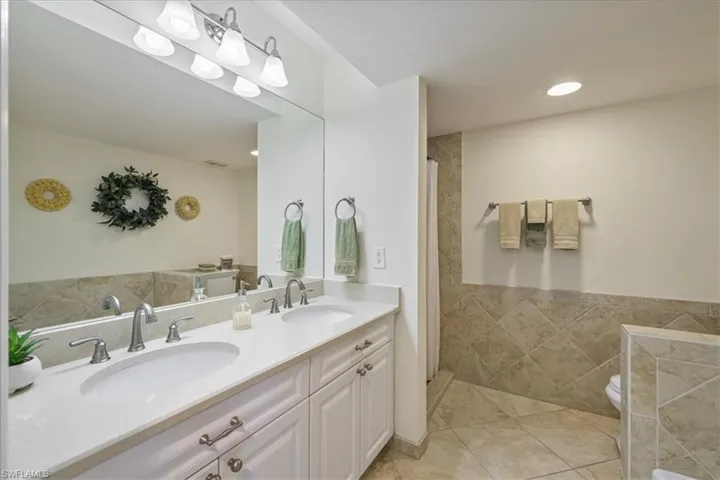 Bathroom with double vanity, recessed lighting, a shower with curtain, and light tile patterned flooring