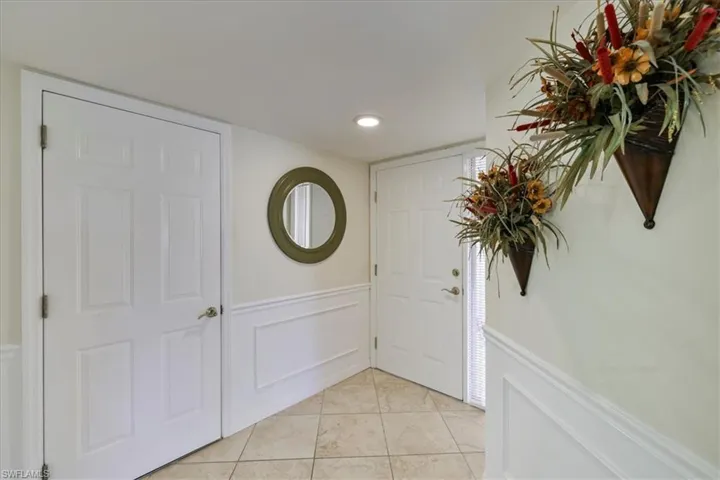 Entrance foyer featuring a decorative wall, a wainscoted wall, light tile patterned floors, and recessed lighting