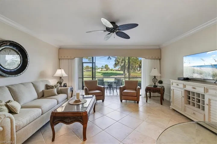 Living area with crown molding, ceiling fan, and light tile patterned floors