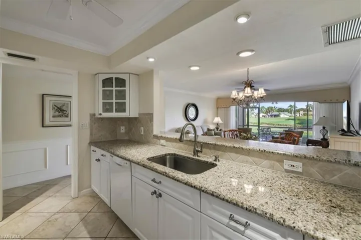 Kitchen with ornamental molding, tasteful backsplash, white cabinetry, light stone countertops, and dishwasher