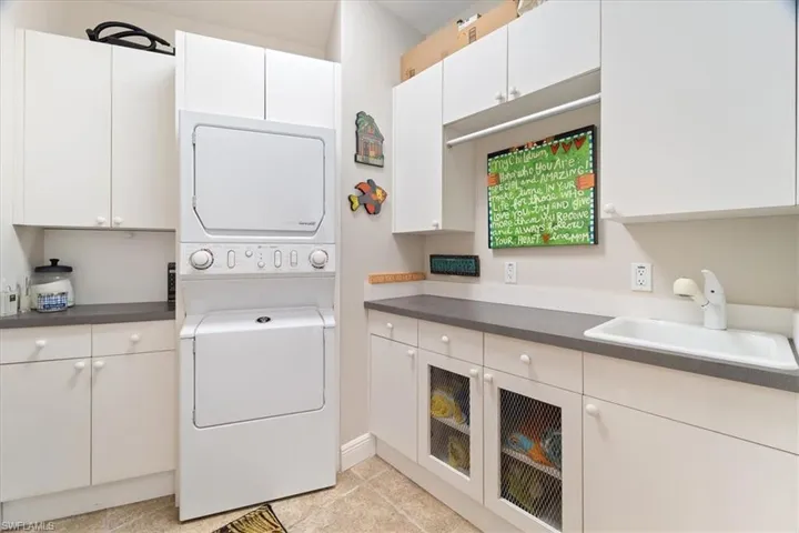 Washroom featuring cabinets, stacked washer and clothes dryer, and sink