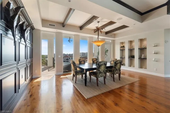 Dining room with beamed ceiling, built in shelves, and hardwood / wood-style flooring