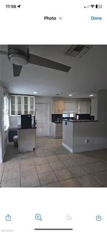 Kitchen featuring dark countertops, a peninsula, light tile patterned floors, and white cabinets