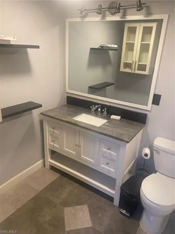 Half bathroom with vanity, a textured wall, and dark tile patterned floors