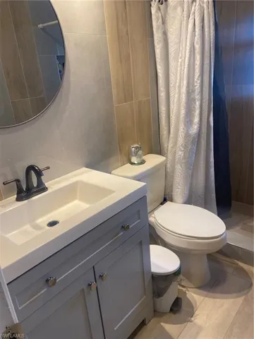 Full bath with tile walls, vanity, and a shower with shower curtain