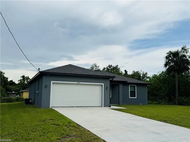 Single story home featuring a front lawn, stucco siding, driveway, and a garage