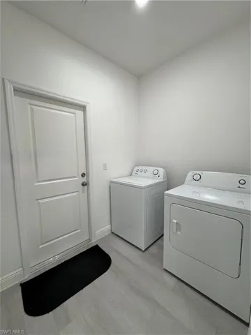 Laundry room featuring light wood finished floors and washing machine and clothes dryer