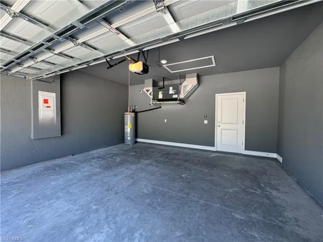 Garage with water heater, a textured wall, a garage door opener, and heating unit