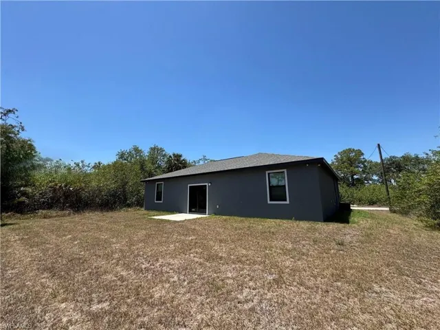 Back of property featuring a patio, stucco siding, and a lawn