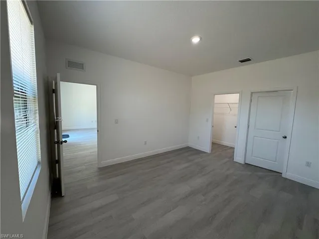 Unfurnished bedroom with a walk in closet and dark wood finished floors