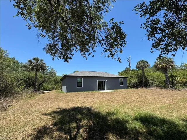 Rear view of house featuring a patio area, a lawn, and stucco siding