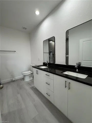 Full bath featuring double vanity, light wood-style flooring, and recessed lighting