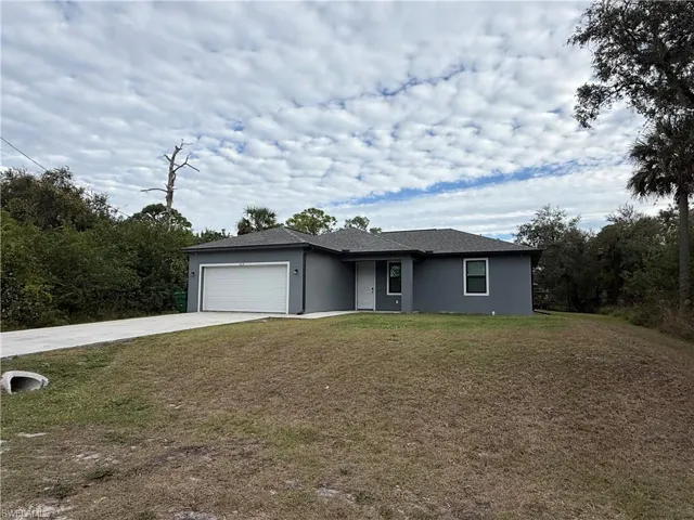 View of front of house featuring concrete driveway, a front yard, stucco siding, and a garage