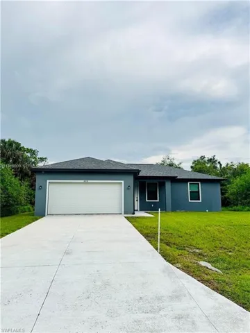 Ranch-style house with an attached garage, a front lawn, concrete driveway, stucco siding, and roof with shingles