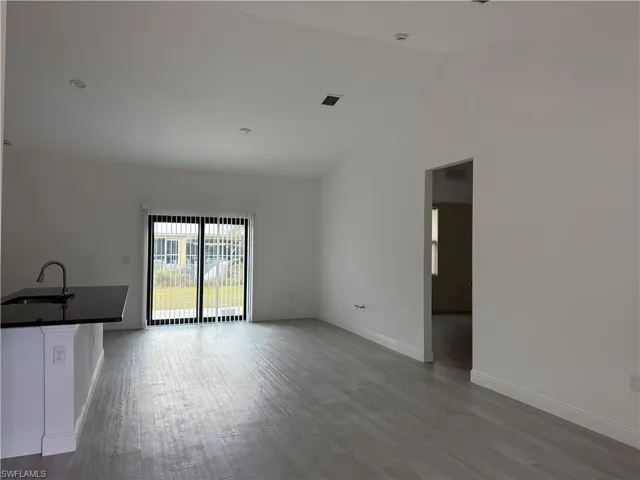 Unfurnished living room featuring dark wood-style flooring and lofted ceiling