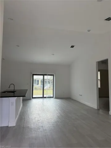 Unfurnished living room featuring a sink and light wood-style floors