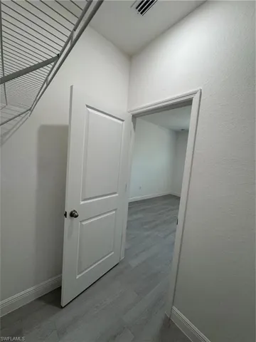 Corridor with a textured wall and light wood-type flooring