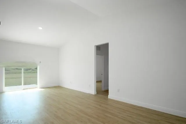 Spare room featuring lofted ceiling and light wood finished floors