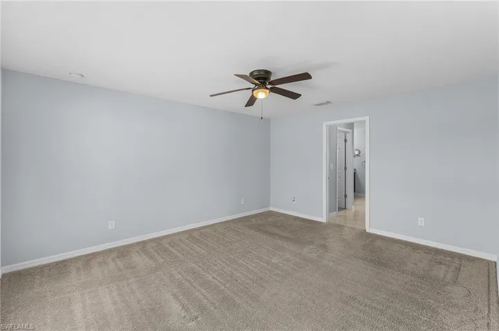 Carpeted empty room featuring ceiling fan