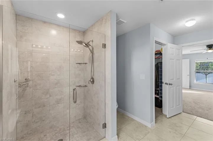 Bathroom featuring tile patterned floors, ceiling fan, and walk in shower