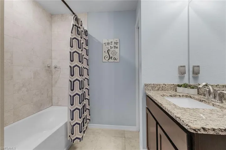 Bathroom featuring tile patterned floors, vanity, and shower / tub combo with curtain