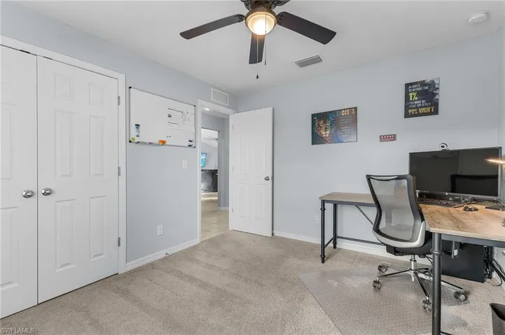 Home office with light carpet and ceiling fan