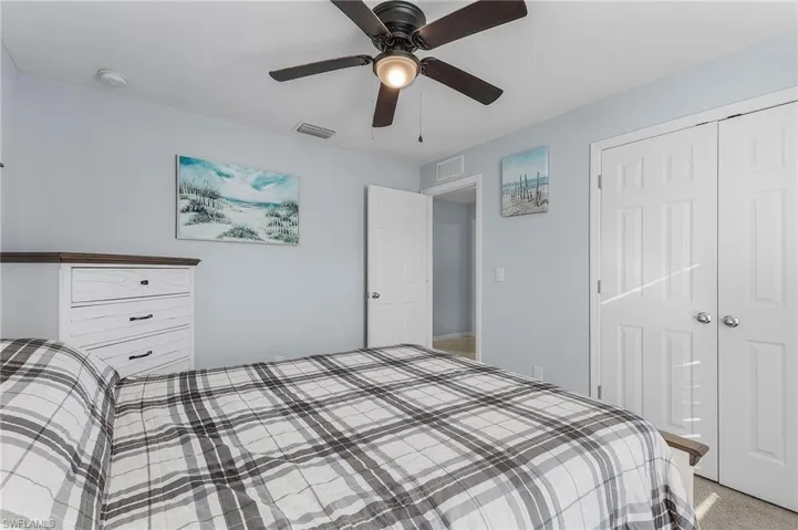 Bedroom with ceiling fan, light carpet, and a closet