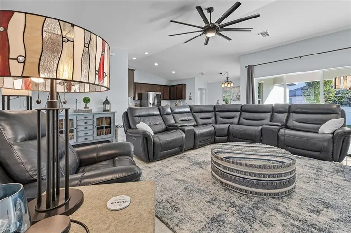 Living room featuring ceiling fan with notable chandelier and lofted ceiling