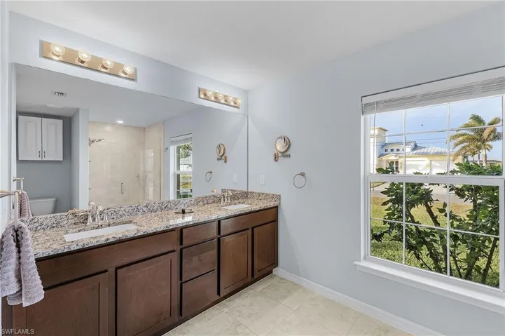 Bathroom with tile patterned floors, plenty of natural light, an enclosed shower, and toilet