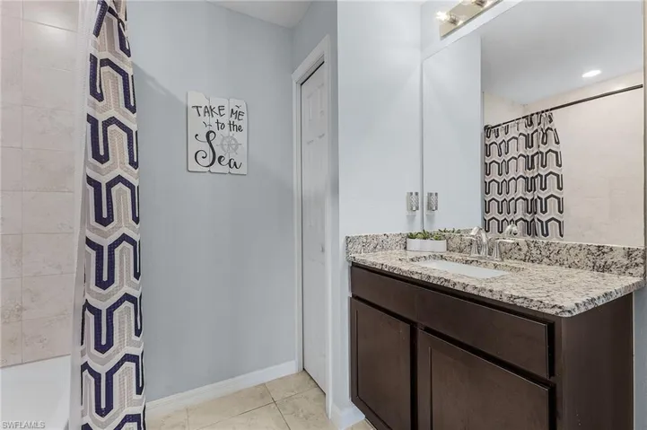 Bathroom featuring tile patterned flooring, vanity, and shower / tub combo