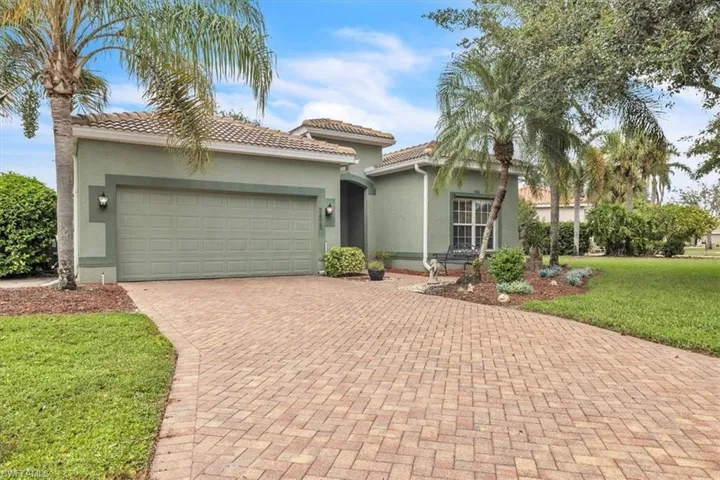 Mediterranean / spanish house with a front yard, stucco siding, decorative driveway, a garage, and a tiled roof