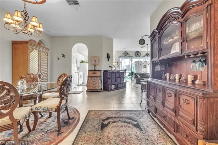 Dining room featuring arched walkways, light tile patterned floors, and a chandelier