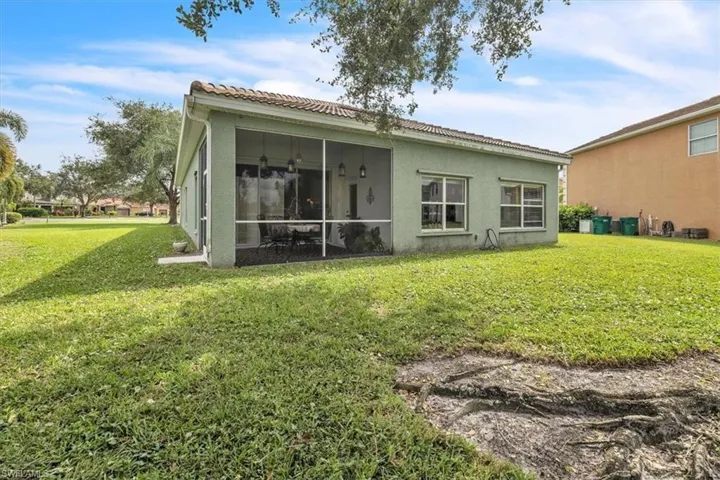 Back of house with a tile roof, a lawn, a sunroom, and stucco siding