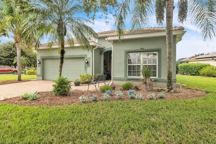 View of front facade with a front yard, stucco siding, decorative driveway, a garage, and a tiled roof