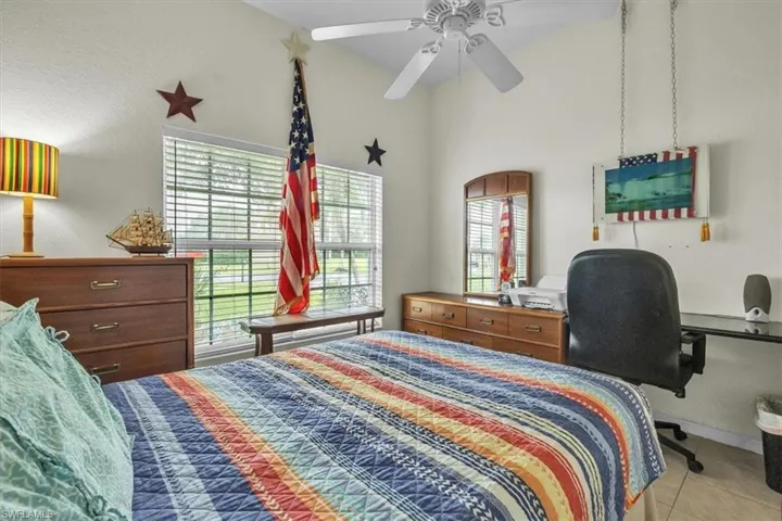 Bedroom with multiple windows, ceiling fan, light tile patterned flooring, and a high ceiling