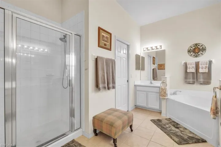 Full bath with vanity, a stall shower, a bath, and light tile patterned floors
