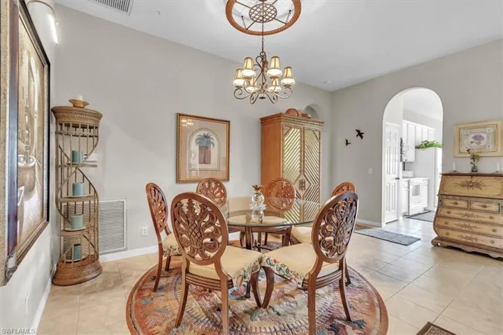 Dining space featuring arched walkways, light tile patterned floors, and a chandelier