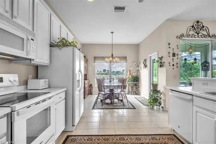 Kitchen with white appliances, light countertops, and white cabinets