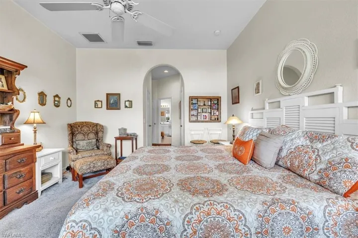 Bedroom with dark carpet, arched walkways, and a ceiling fan