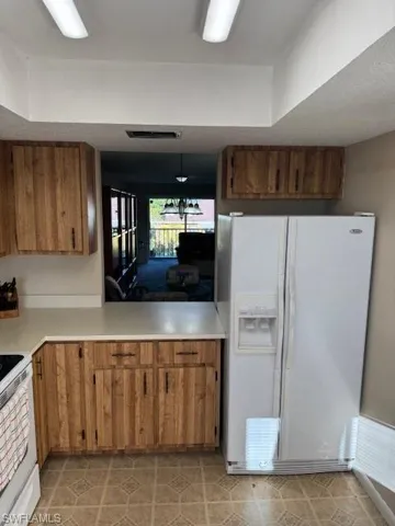 Kitchen featuring refrigerator, brown cabinets, stove, light countertops, and a textured ceiling