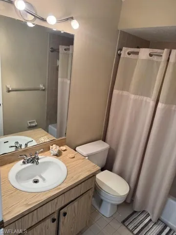 Bathroom featuring light tile patterned floors, vanity, and shower / bathtub combination with curtain